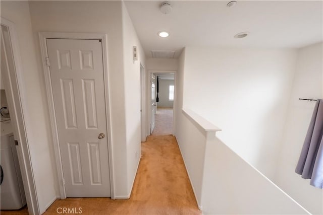 corridor featuring attic access, baseboards, and light colored carpet