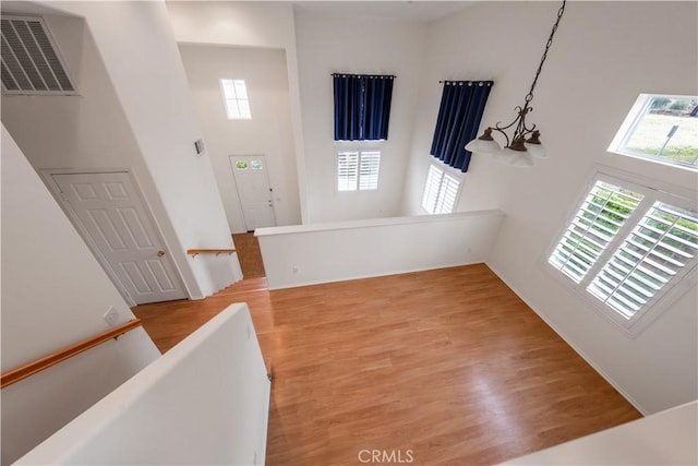 foyer entrance featuring baseboards, light wood-style flooring, visible vents, and a high ceiling