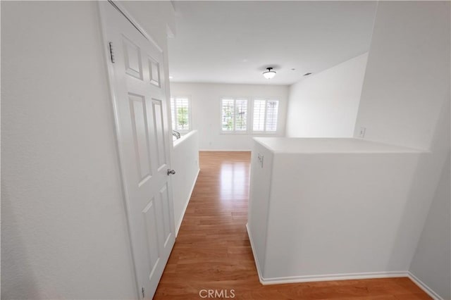 corridor with baseboards and light wood-type flooring