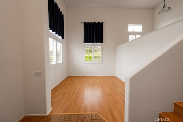 unfurnished room with baseboards, wood finished floors, and stairs