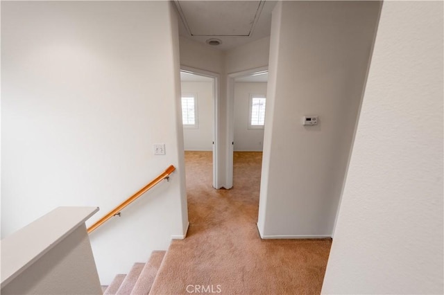 corridor featuring attic access, carpet flooring, baseboards, and an upstairs landing
