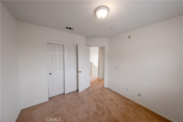 unfurnished bedroom with a closet, visible vents, baseboards, and light carpet