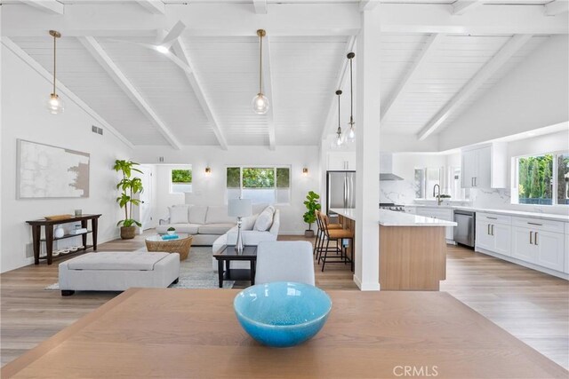 dining room with light wood-style flooring, high vaulted ceiling, plenty of natural light, beam ceiling, and wood ceiling