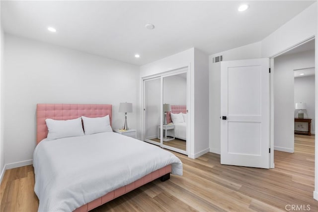 bedroom featuring a closet, baseboards, recessed lighting, and light wood-style floors