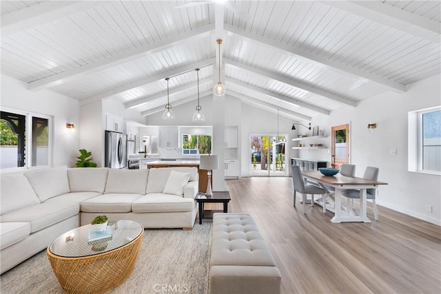 living area featuring plenty of natural light, light wood finished floors, baseboards, beamed ceiling, and high vaulted ceiling