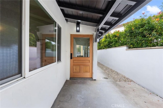 view of exterior entry featuring stucco siding and fence