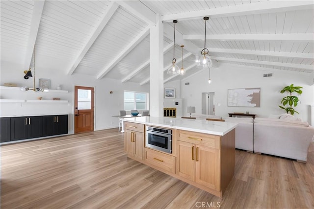 kitchen with open floor plan, light wood-style floors, stainless steel oven, light brown cabinetry, and beamed ceiling
