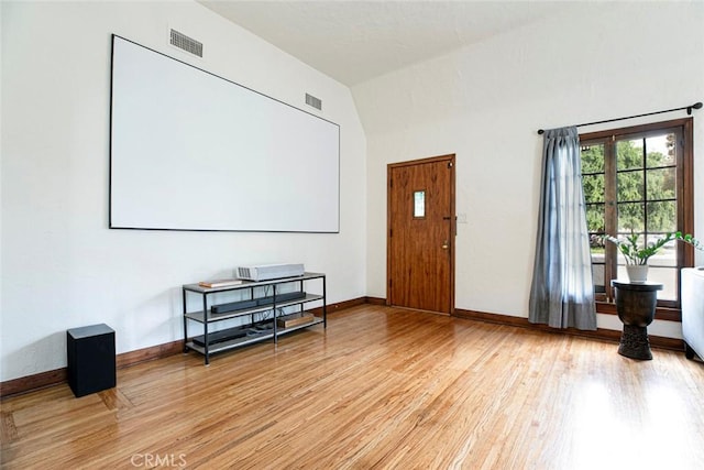 interior space with light wood-type flooring, baseboards, lofted ceiling, and visible vents