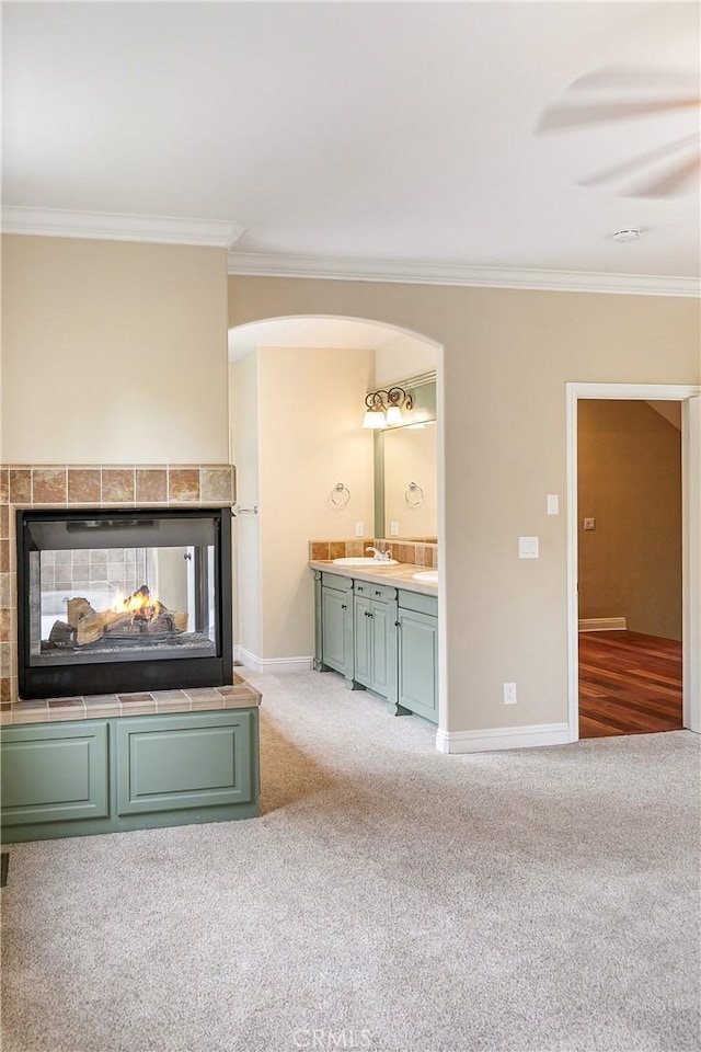 unfurnished living room with light carpet, a multi sided fireplace, baseboards, and ornamental molding