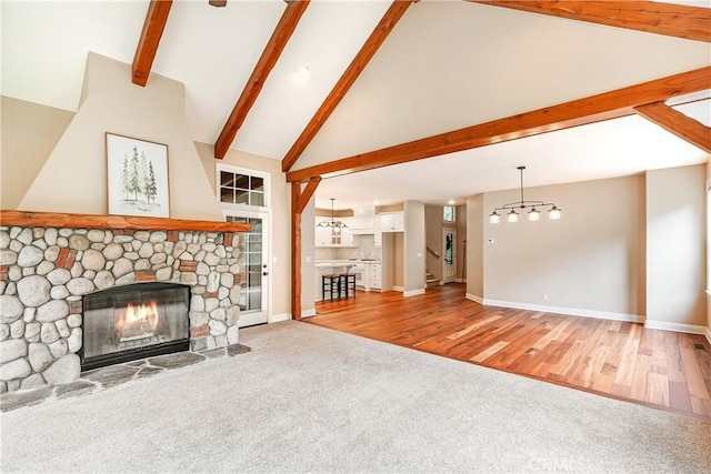 unfurnished living room with an inviting chandelier, a fireplace, carpet floors, baseboards, and beam ceiling