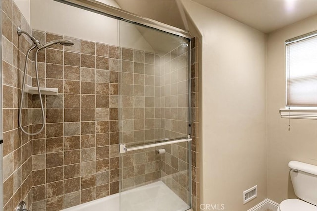 full bath featuring a tile shower, toilet, and baseboards