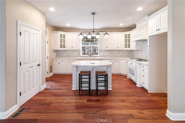 kitchen with white cabinetry, a sink, white appliances, and visible vents