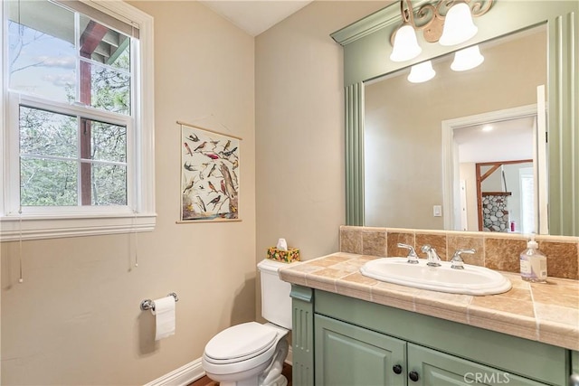 bathroom with toilet, vanity, and plenty of natural light