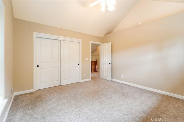 unfurnished bedroom with baseboards, a closet, vaulted ceiling, a ceiling fan, and carpet