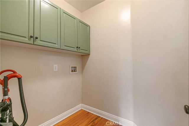 clothes washing area with cabinet space, light wood-style flooring, hookup for a washing machine, and baseboards