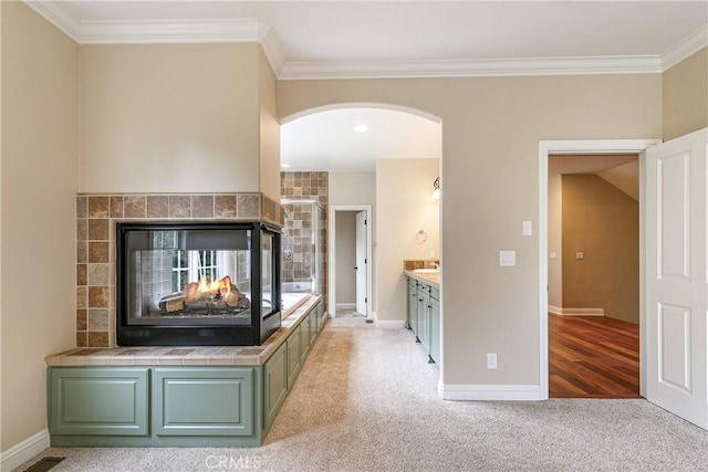 living room featuring a tiled fireplace, baseboards, and crown molding