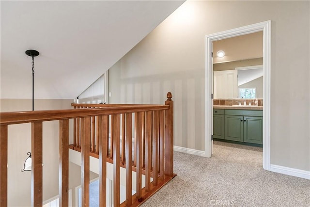 hall with light carpet, vaulted ceiling, and baseboards