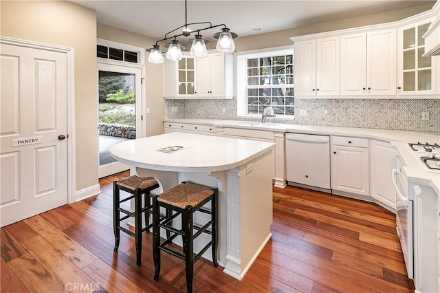 kitchen featuring a breakfast bar area, a healthy amount of sunlight, a sink, and white appliances