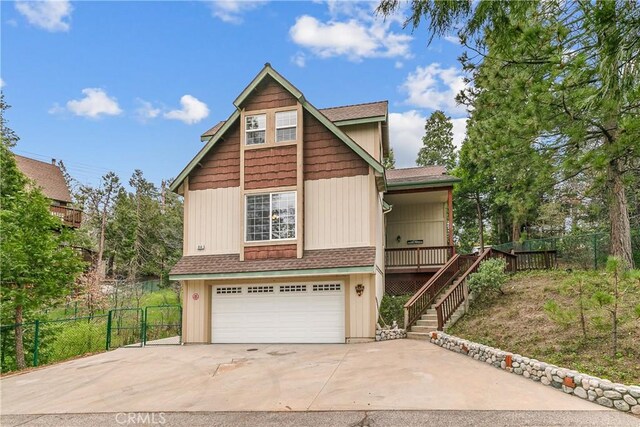 view of front of house with stairway, roof with shingles, fence, an attached garage, and driveway