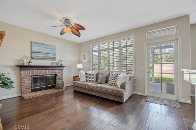 living area featuring ceiling fan, hardwood / wood-style flooring, baseboards, and a fireplace