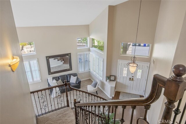 foyer featuring baseboards, a towering ceiling, and carpet