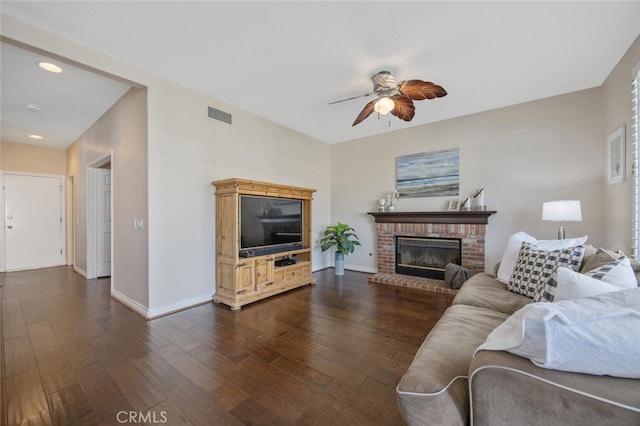 living area with a fireplace, a ceiling fan, visible vents, baseboards, and dark wood-style floors
