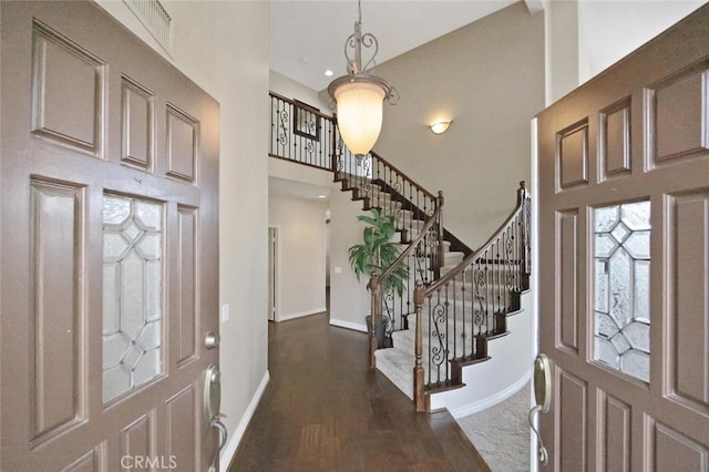 foyer with a high ceiling, wood finished floors, baseboards, and stairway