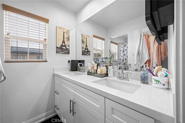 bathroom featuring a sink, baseboards, and double vanity