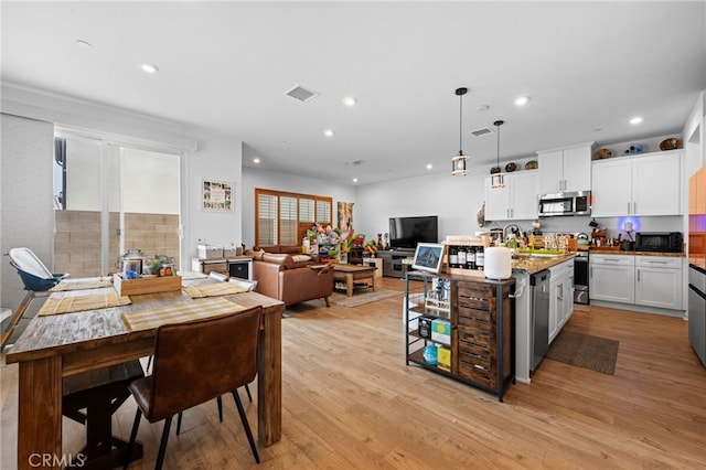 kitchen with visible vents, an island with sink, white cabinetry, light wood-style flooring, and stainless steel appliances