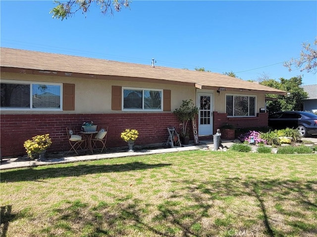 ranch-style home with a front yard, brick siding, and stucco siding
