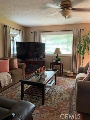 living area with a ceiling fan and a textured ceiling