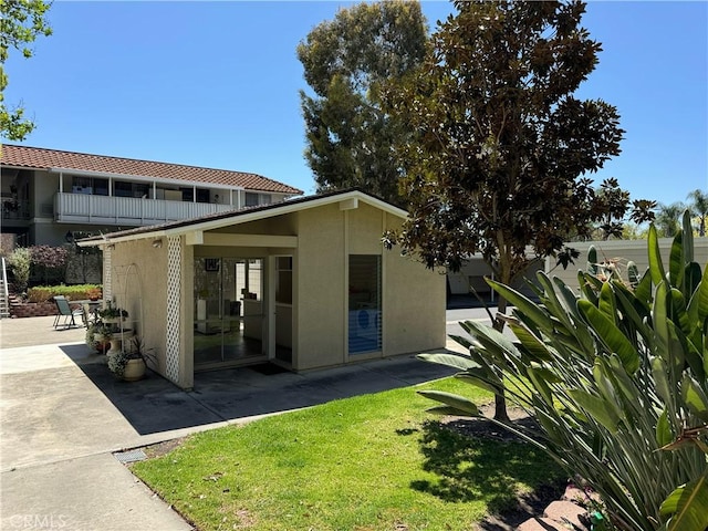 661 Avenida Sevilla Unit O, Laguna Woods, CA 92637 - rear view of property featuring a patio, stucco siding, and a yard