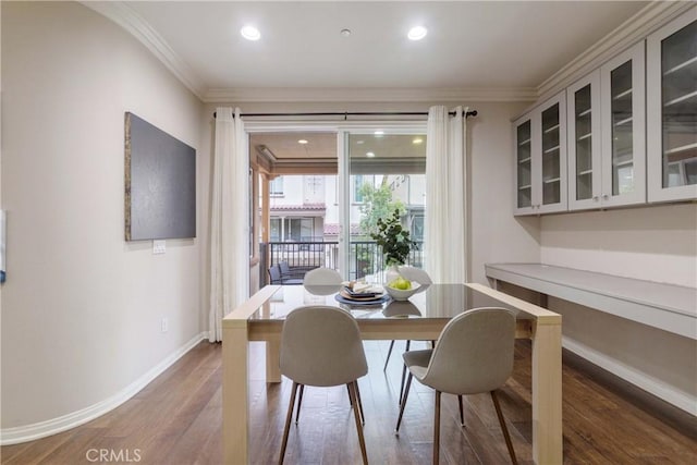 dining room featuring baseboards, crown molding, wood finished floors, and recessed lighting