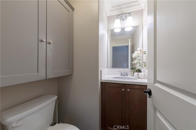bathroom with toilet, vanity, and ornamental molding