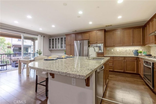 kitchen with a kitchen bar, dark wood finished floors, appliances with stainless steel finishes, and a sink