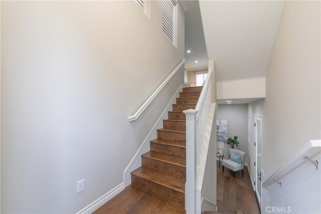 staircase with visible vents, wood finished floors, a high ceiling, and recessed lighting