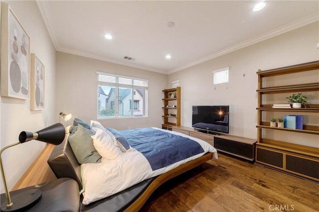 bedroom with wood finished floors, visible vents, ornamental molding, and multiple windows