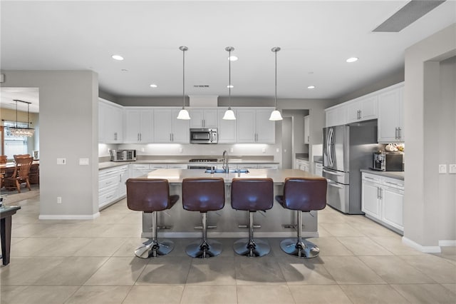 kitchen with white cabinetry, stainless steel appliances, a kitchen island with sink, and a sink