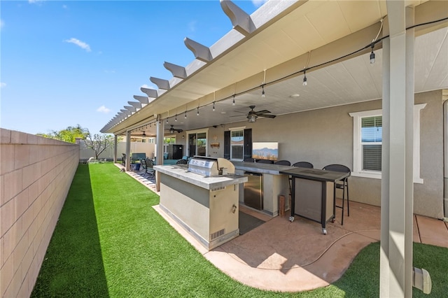 view of patio featuring grilling area, an outdoor kitchen, a fenced backyard, and ceiling fan