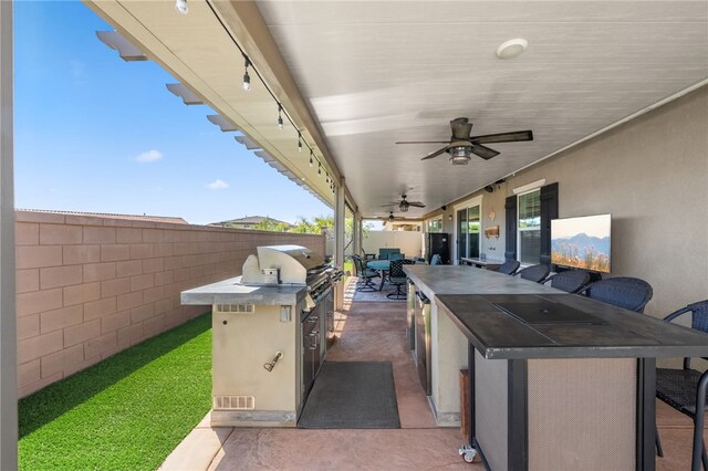 view of patio / terrace with area for grilling, a fenced backyard, ceiling fan, visible vents, and outdoor wet bar