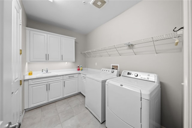 washroom with washing machine and clothes dryer, cabinet space, a sink, and light tile patterned flooring