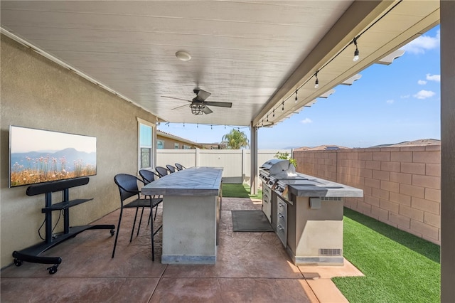 view of patio / terrace with a fenced backyard, ceiling fan, outdoor wet bar, and an outdoor kitchen