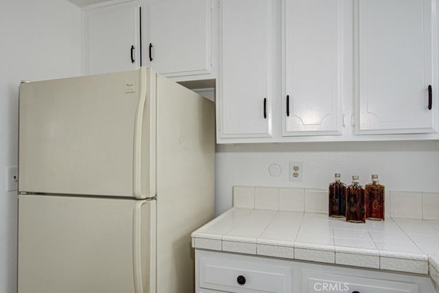 2399 Via Mariposa W Unit 2E, Laguna Woods, CA 92637 - kitchen with freestanding refrigerator, white cabinets, and tile countertops