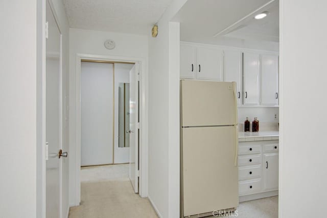 2399 Via Mariposa W Unit 2E, Laguna Woods, CA 92637 - kitchen featuring freestanding refrigerator, white cabinets, and tile countertops
