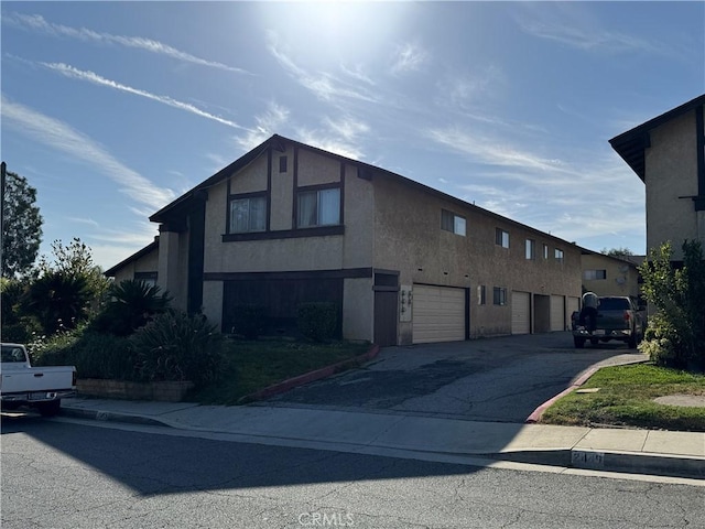 2453 S Ridgewood Dr, West Covina, CA 91792 - view of side of property with stucco siding, an attached garage, and asphalt driveway