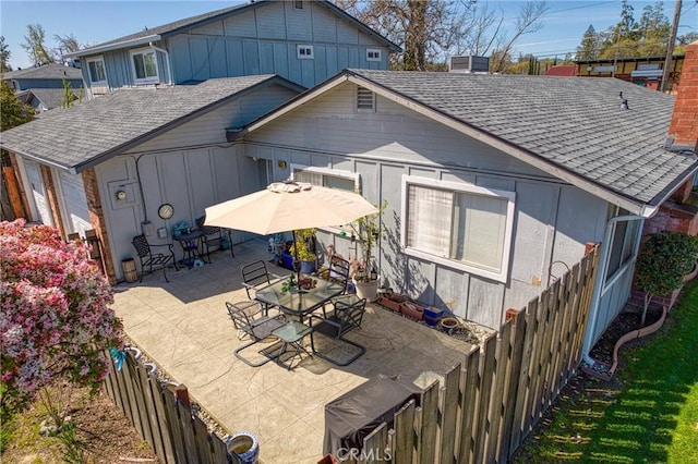 back of house with a patio, roof with shingles, and a fenced backyard