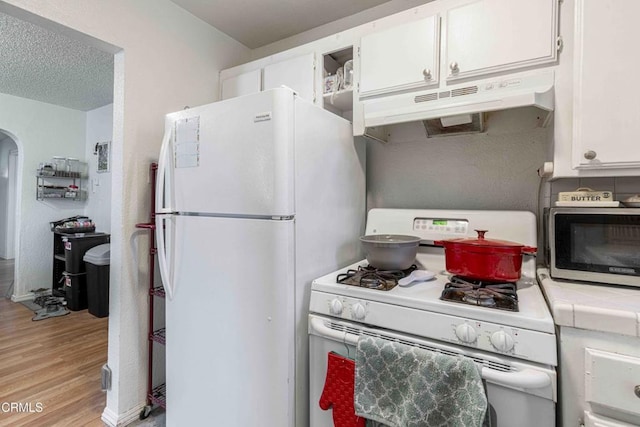 510 Decatur St, Bakersfield, CA 93308 - kitchen with tile counters, white appliances, light wood-style flooring, white cabinets, and under cabinet range hood