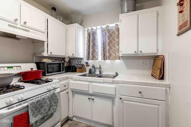 510 Decatur St, Bakersfield, CA 93308 - kitchen featuring tile countertops, white gas stove, white cabinets, under cabinet range hood, and stainless steel microwave