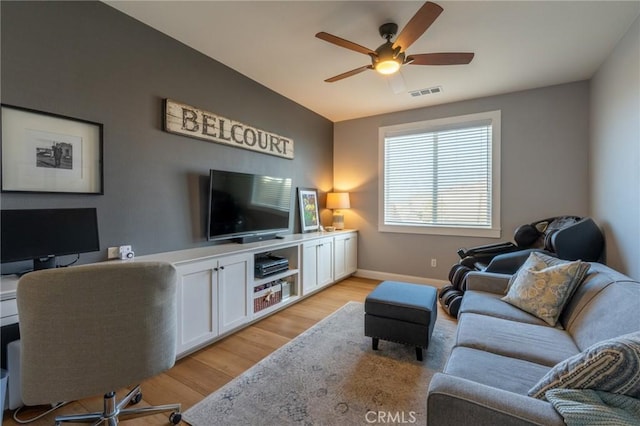 living area featuring light wood-style flooring, visible vents, baseboards, and ceiling fan