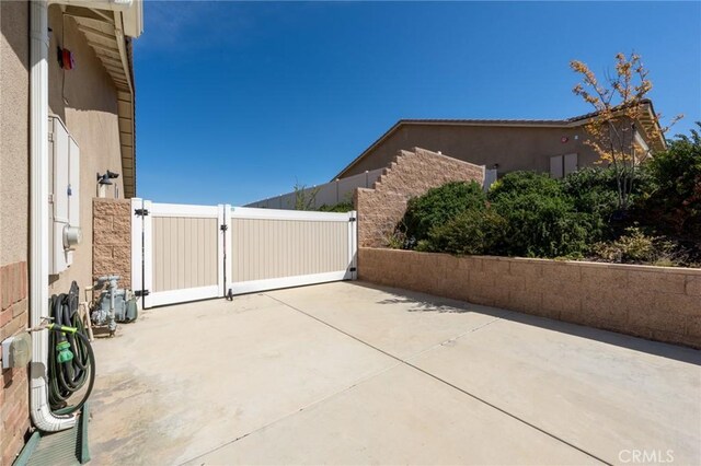 view of home's exterior with a gate, fence, a patio area, and stucco siding